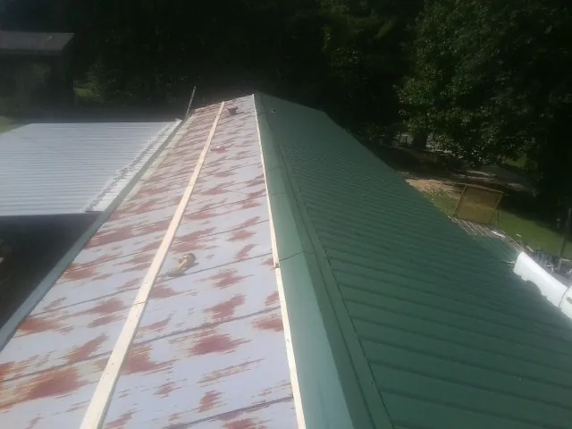 Old rusted panels beside newly installed green metal roofing — Wind Damage Roof Repair by Roofing Brothers in Chattahoochee