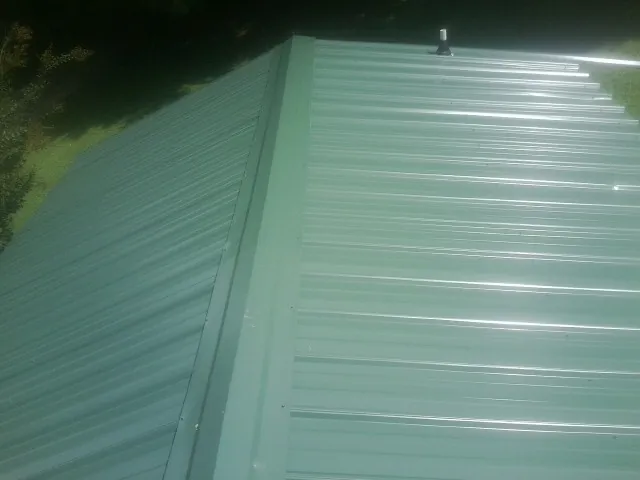 New green metal panels meeting at the ridge of a roof — Flat Roof Repair work by our crew in Chattahoochee