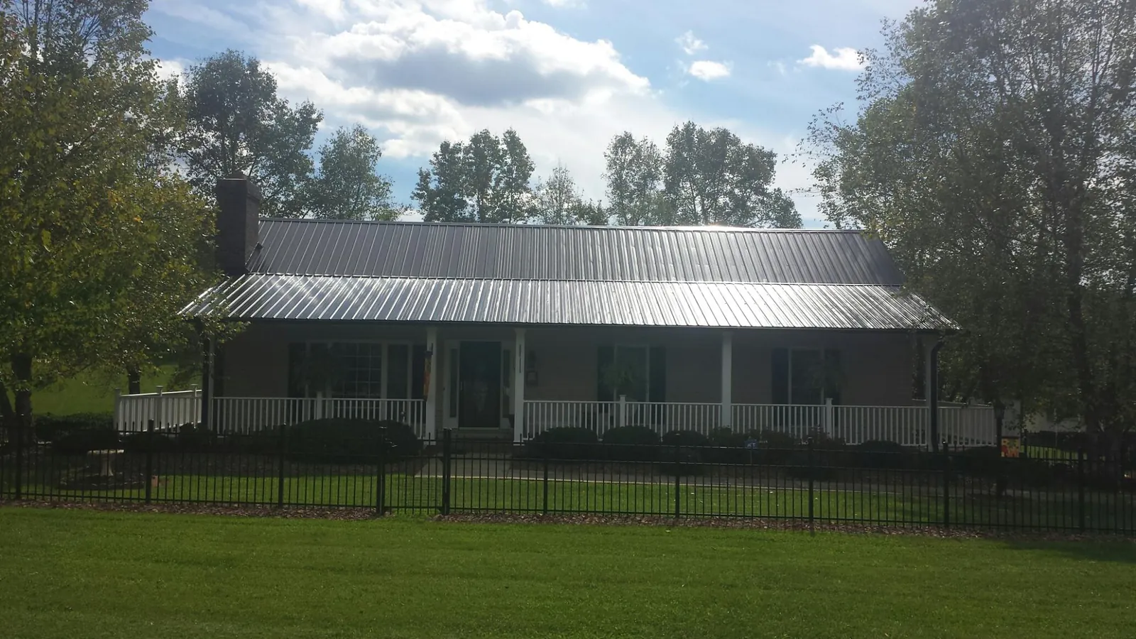 Gray metal roof on a brick ranch with a full width front porch — Gutter Guard Installation work by our crew in Chattahoochee