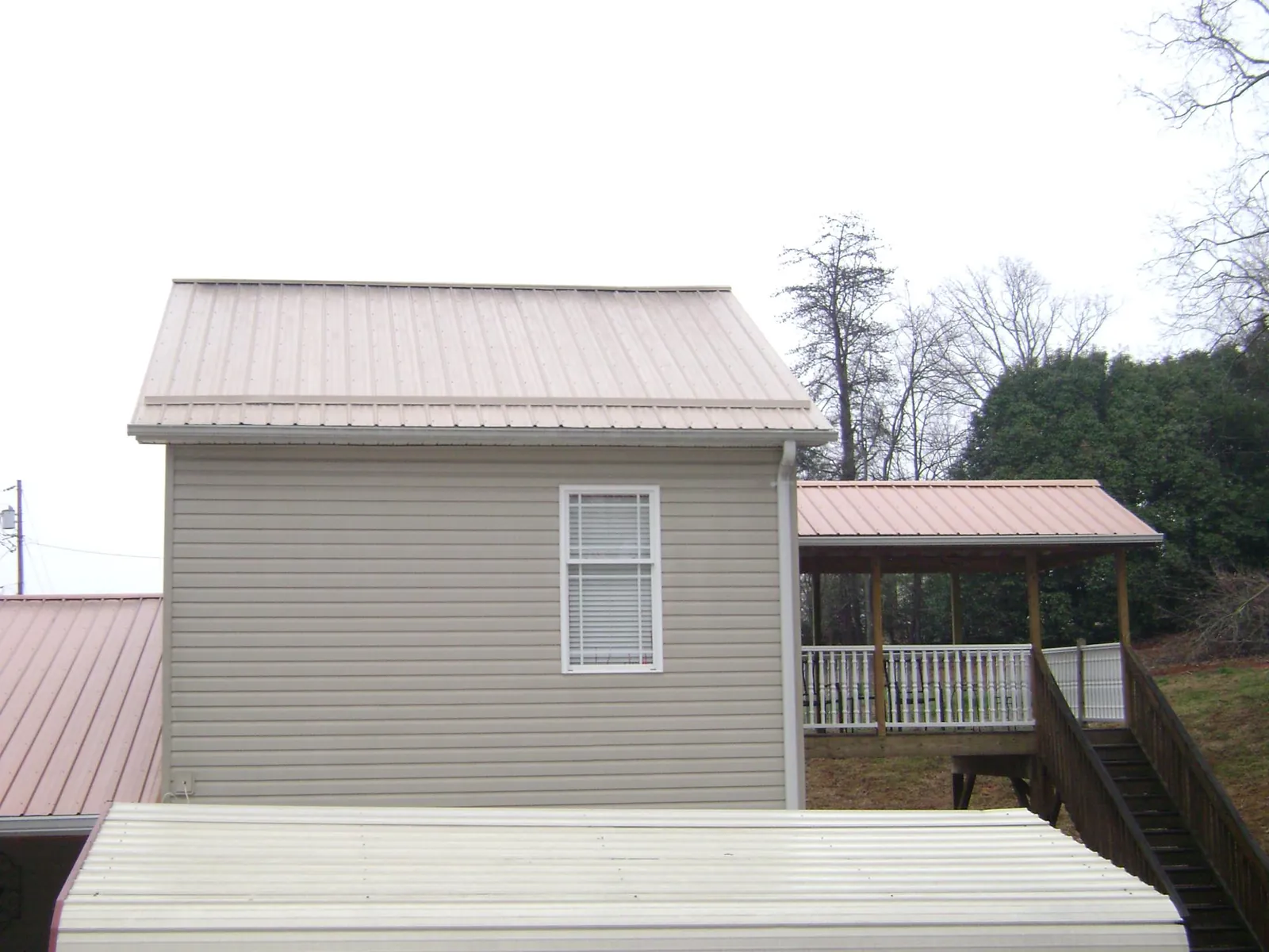 Tan metal roofs on a two story addition and attached porch, from a Roof Replacement job in Chattahoochee