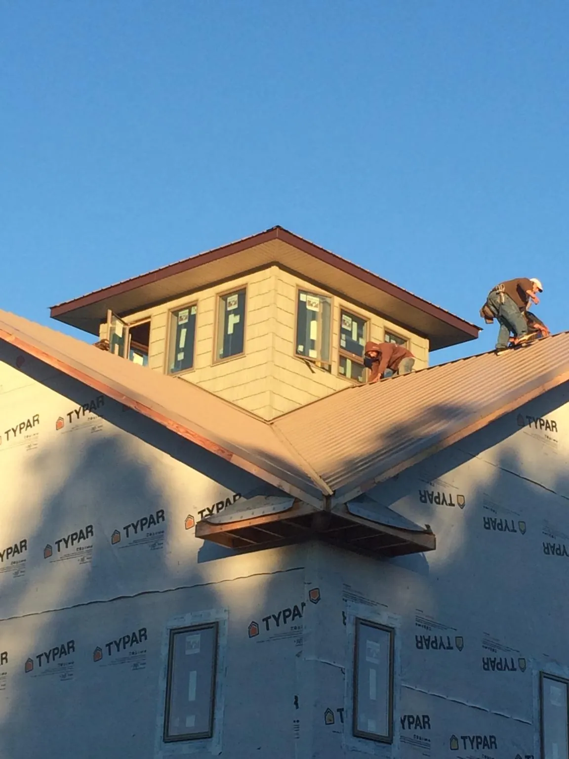 Roofers working around a rooftop cupola on a new metal roof at sunset — Roof Waterproofing in Chattahoochee by Roofing Brothers